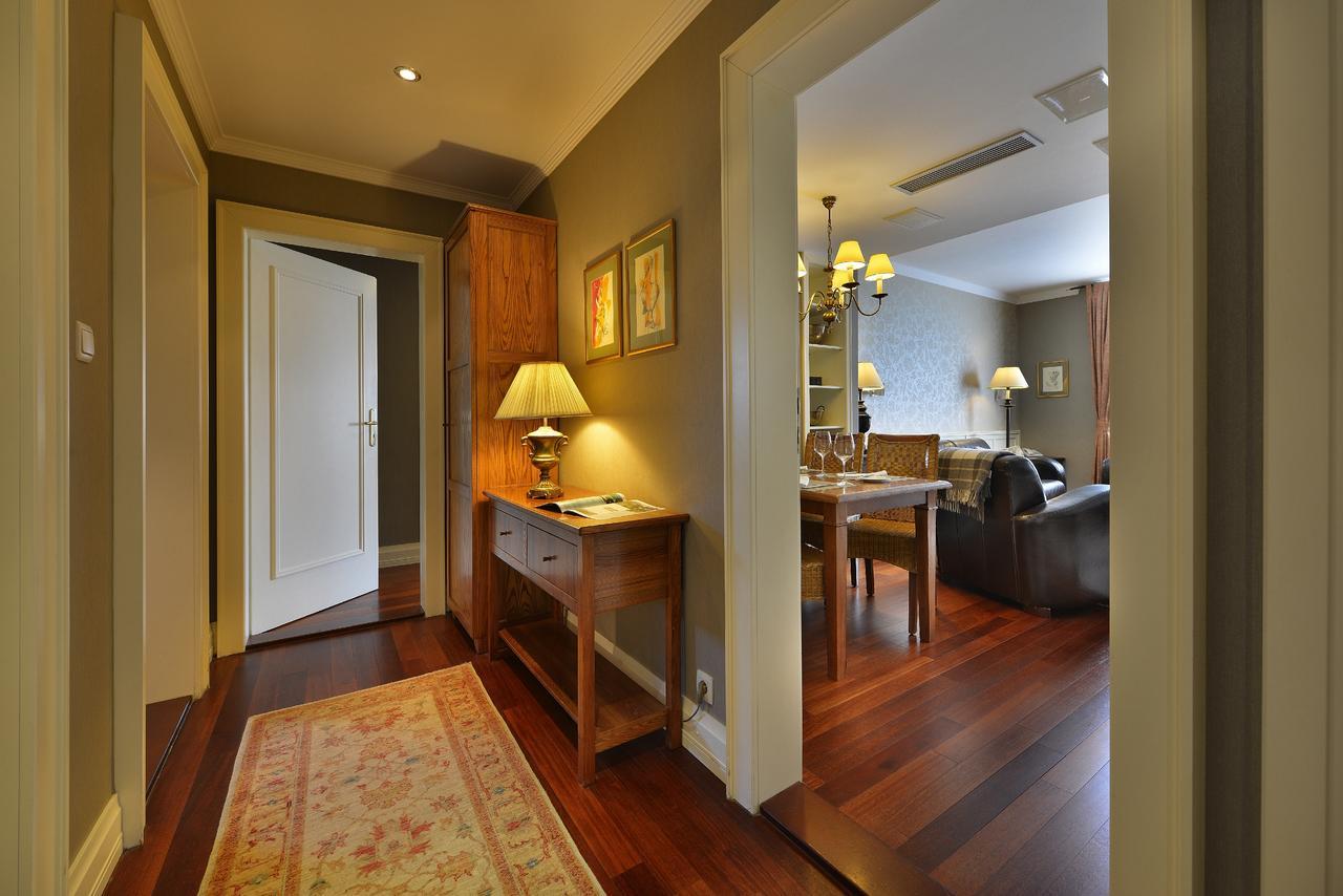 Marrol'S Boutique Hotel Bratislava Exterior foto The photo shows a hallway or entrance area leading into a cozy living space. The walls are painted in a warm, neutral tone, and the floor is made of hardwood, giving it a rich appearance. To the left, there is a wooden console table topped with a lam